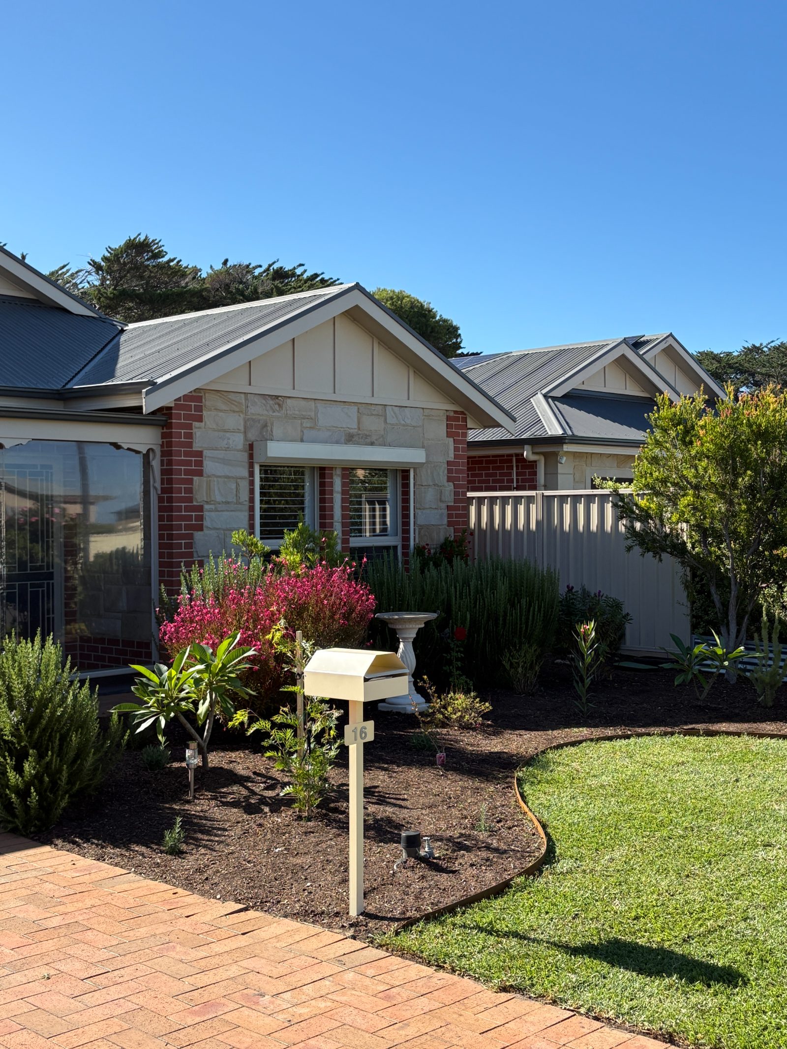 Brick home with a planted front garden, mulch and curved lawn edging