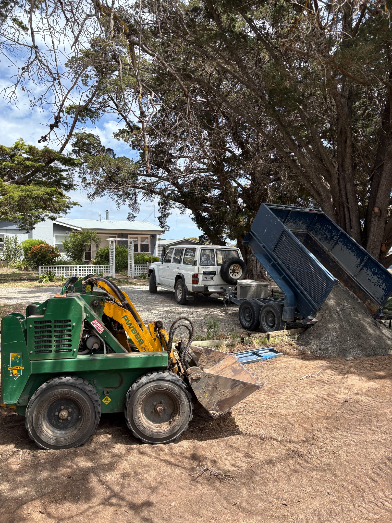 Mini loader and tipping trailer on site, delivering material for a job